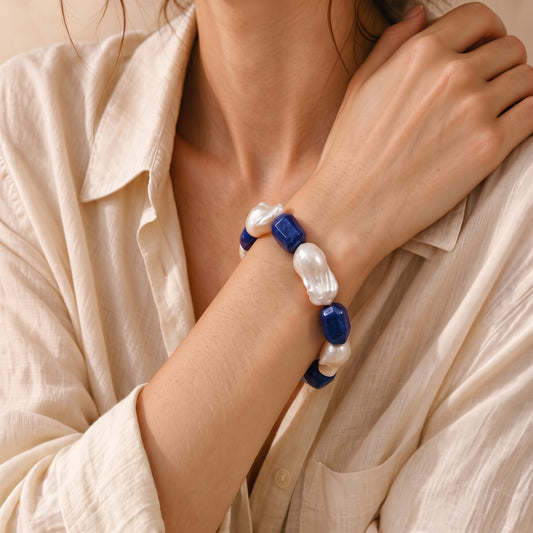 Model wearing chunky baroque pearl and lapis lazuli bracelet with neutral linen shirt