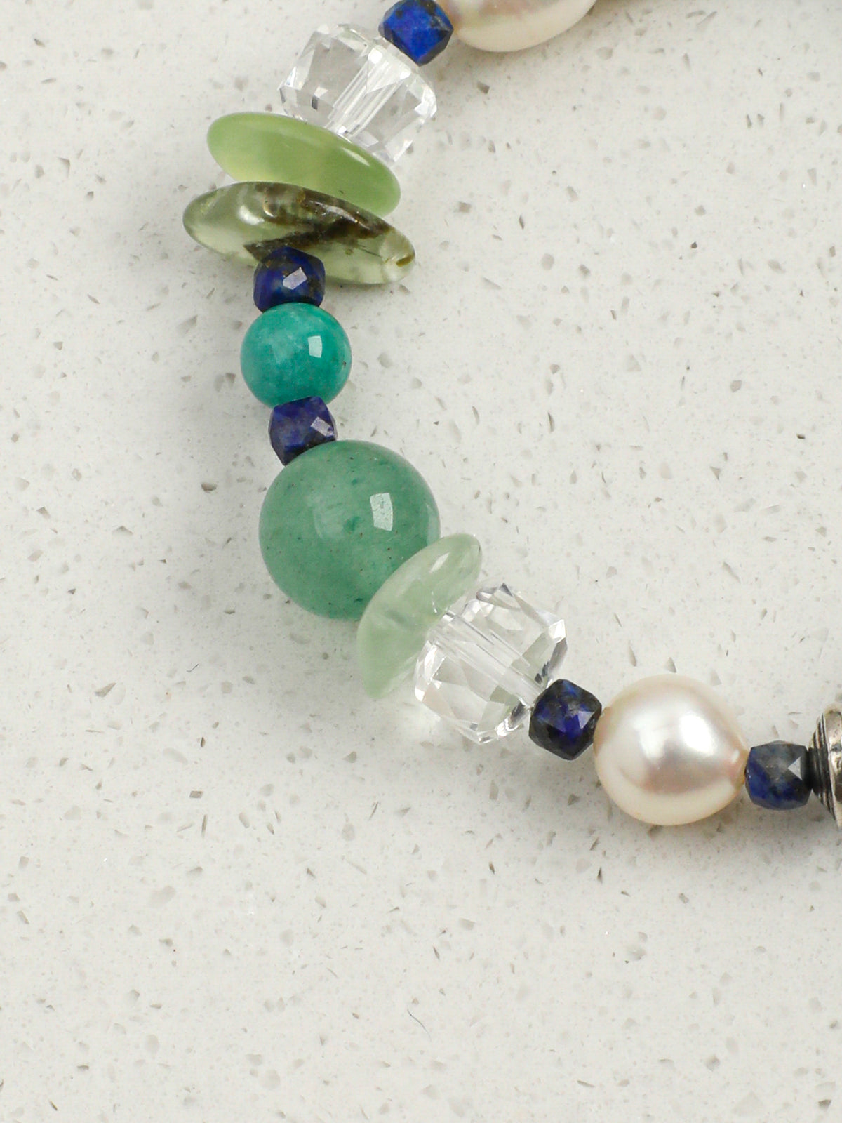 Macro detail of faceted clear quartz wheel beads and translucent green prehnite chips