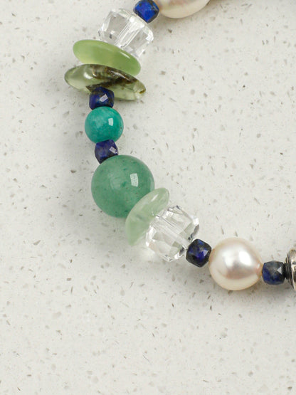 Macro detail of faceted clear quartz wheel beads and translucent green prehnite chips