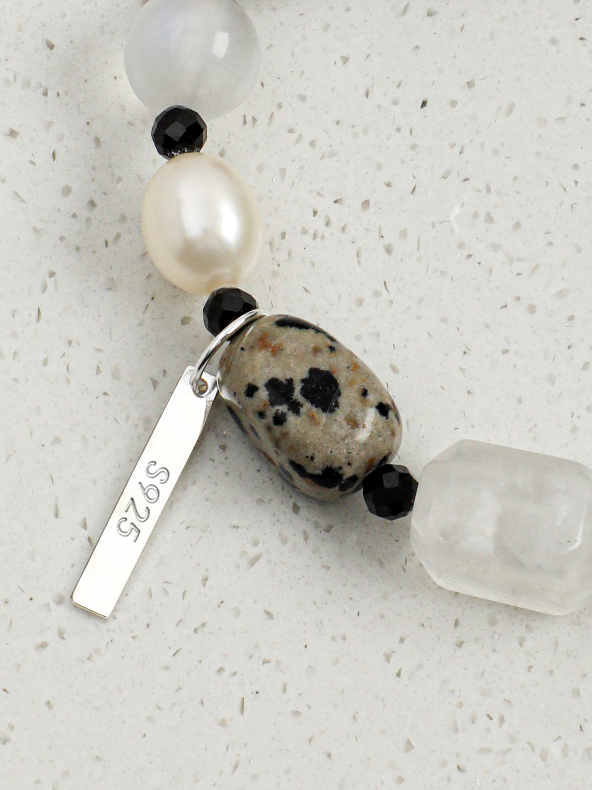 Close up of engraved S925 sterling silver logo charm and durable bracelet craftsmanship