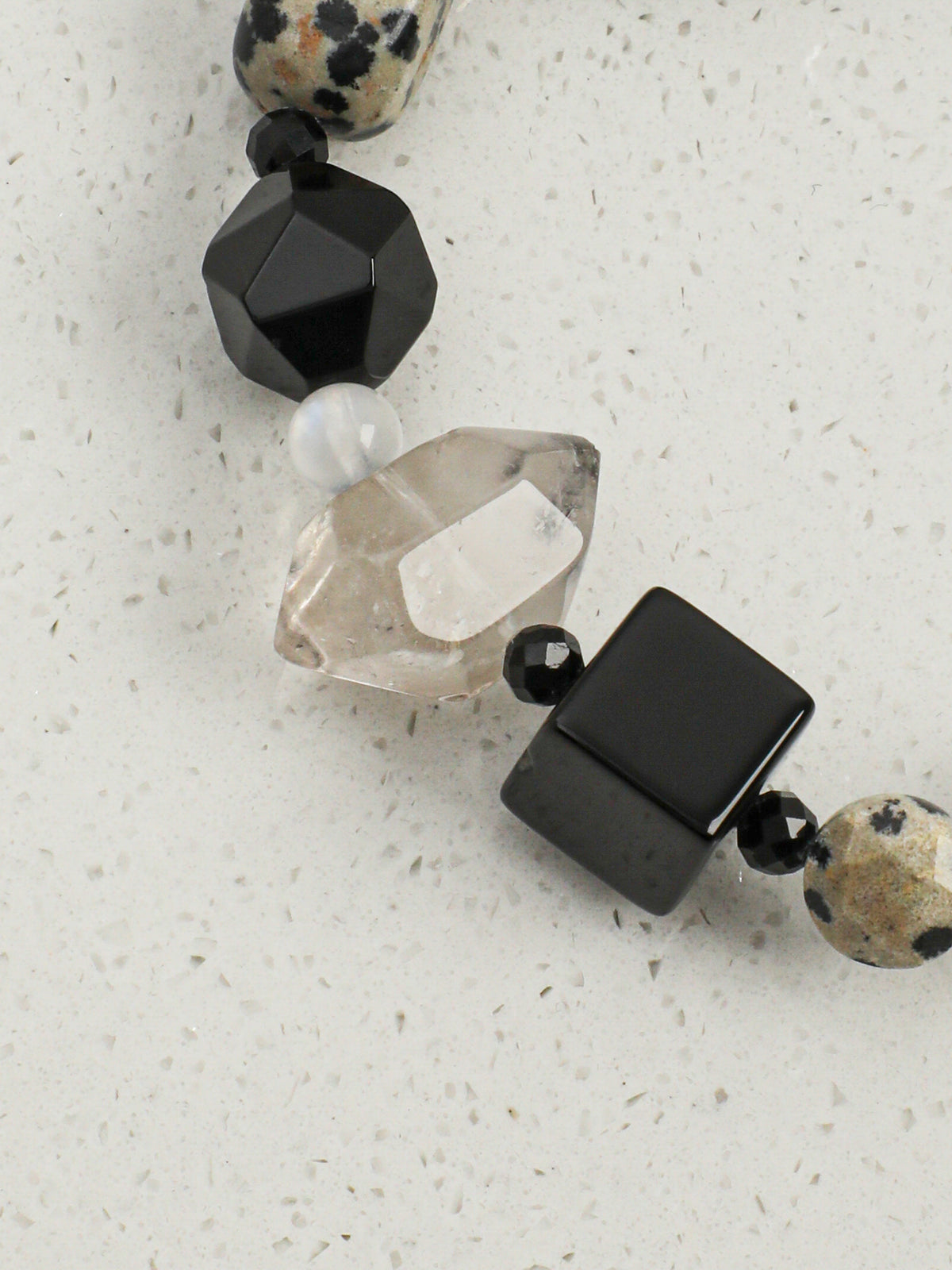 Close up of faceted black agate cube and barrel beads with geometric texture