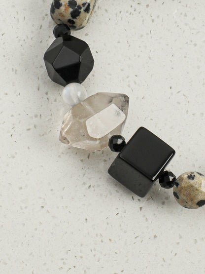 Close up of faceted black agate cube and barrel beads with geometric texture