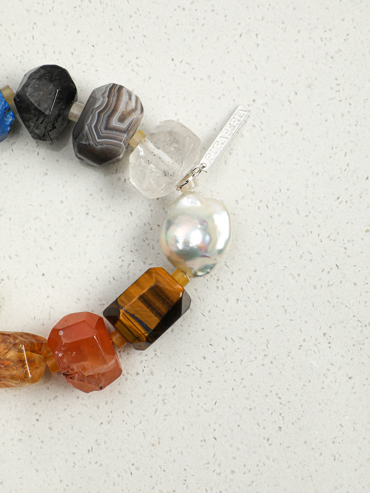 Macro detail of luminous chunky baroque pearl and faceted golden tiger eye stone on bracelet