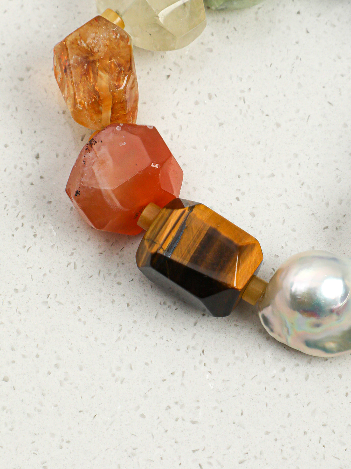 Macro detail of luminous chunky baroque pearl and faceted golden tiger eye stone on bracelet