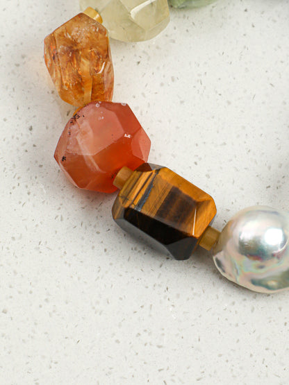 Macro detail of luminous chunky baroque pearl and faceted golden tiger eye stone on bracelet