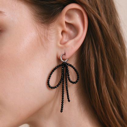 Model wearing 7.5cm black tourmaline bow drop earrings in autumn street style